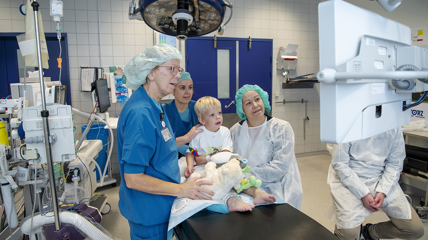 Lille dreng på operationsstue med forælder og personale