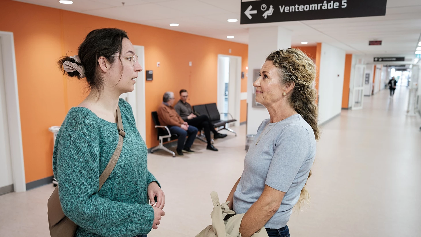 Patient og pårørende i dialog på gangen