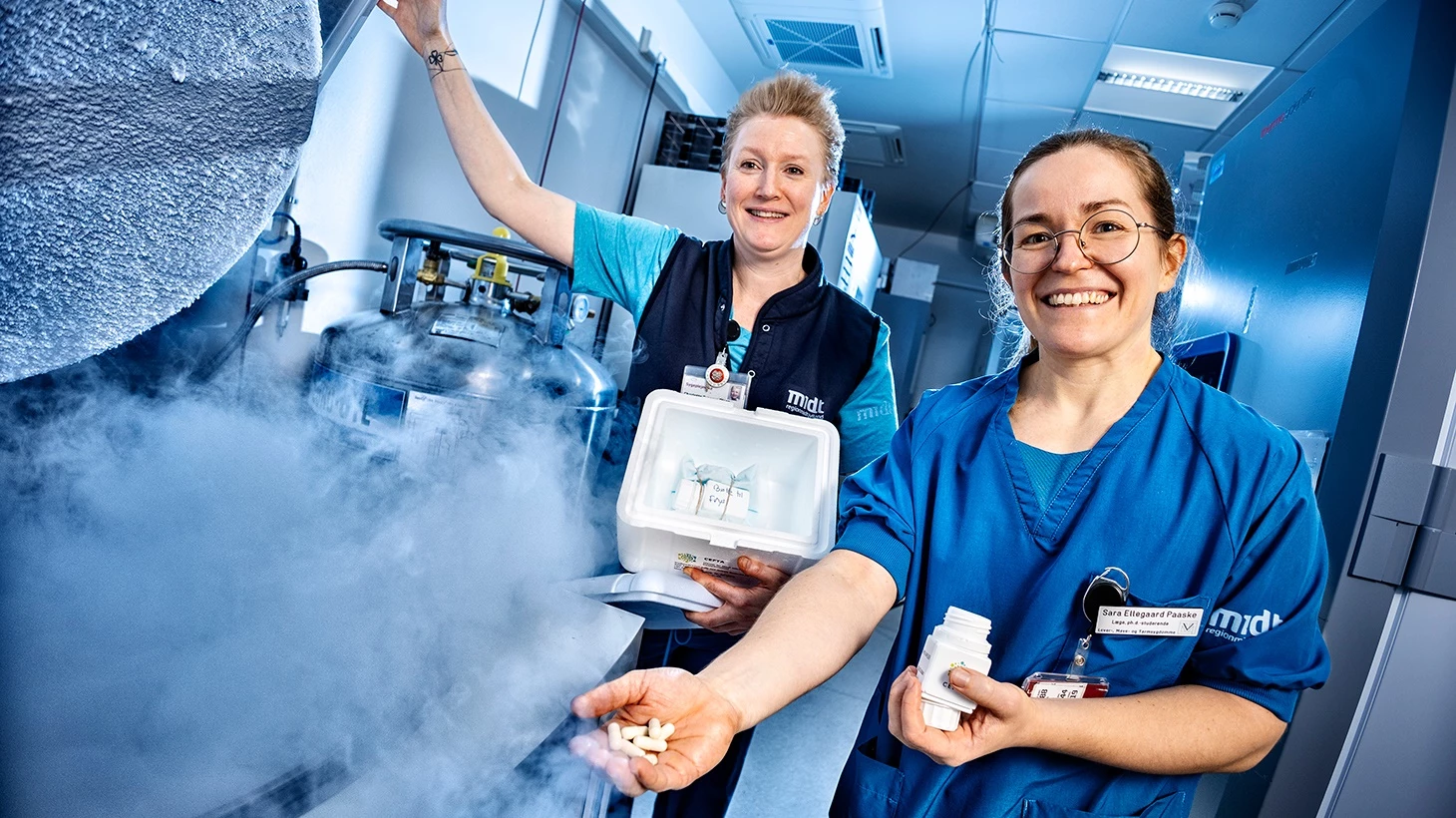 Sygeplejerske Charlotte Braarup Olsen og læge Sara Ellegaard Paaske viser ved en -80 graders fryser nogle af de kapsler og den fryseboks, som patienterne får med hjem.