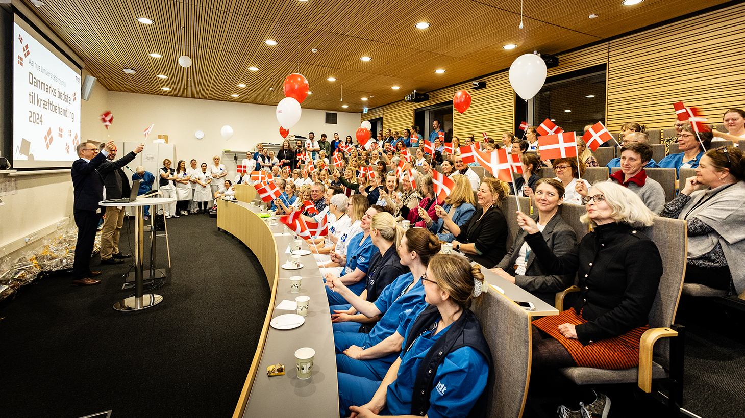 Gruppe af medarbejdere fejrer kåring med flag